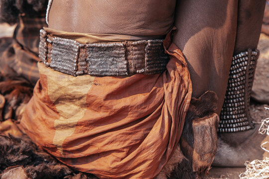 Close-up of Himba woman wearing traditional belt and metal anklets, Angola