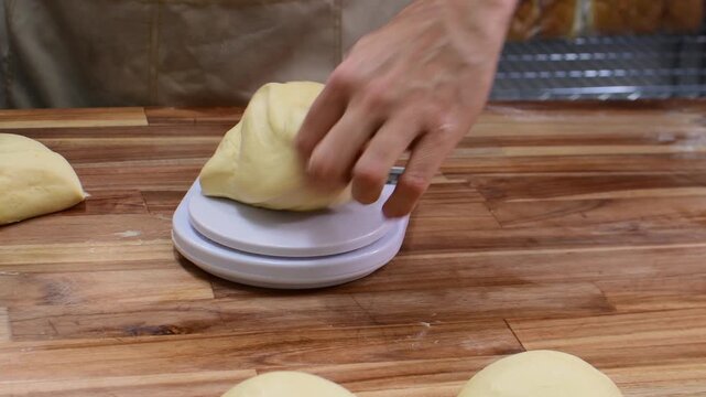 Hand weighs dough on scale for baking bread in cozy kitchen setting