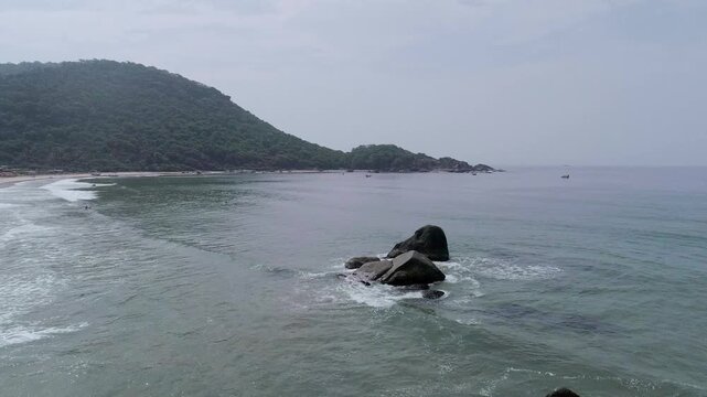 Low angle aerial drone shot moving forward toward coastal mountains at Agonda Beach, South Goa, India
