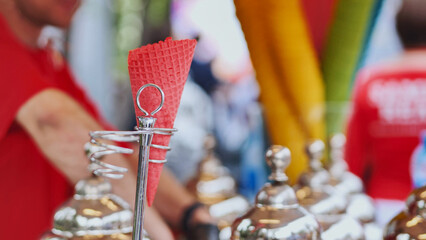 Naklejka premium Refreshing red ice cream cone waiting on a metal stand at a street food market