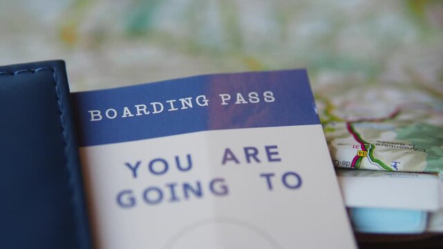 Selective focus of boarding pass inside passport cover on travel map for vacation planning