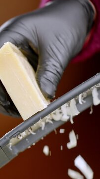 Chef grates cheese. Professional prepares garnish with finesse. Home cook meticulously adds finishing touches with textured rind and wedge