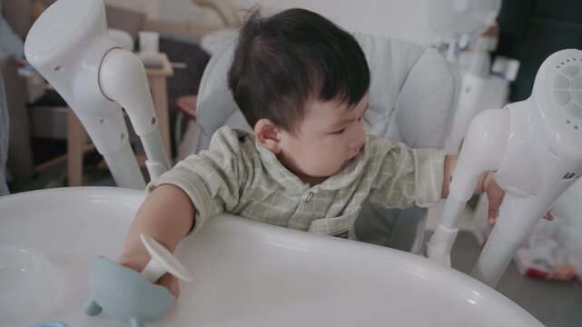 4K Asian mother feeding her six month old baby boy with a spoon at home in morning.
