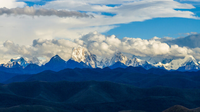 Snow-covered peaks of Mount Gongga (Minya Konka) partially hidden beneath thick, rolling cloud layers in western China. 
