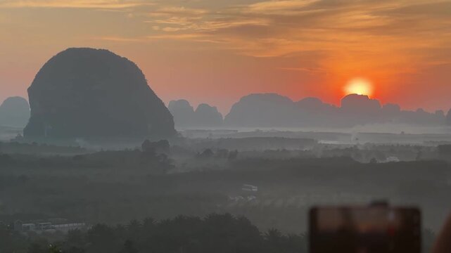 Bright sunrise above limestone mountains and misty valley at Din Daeng Doi in Krabi Thailand with warm sunlight, soft haze, layered terrain, and calm tropical landscape
