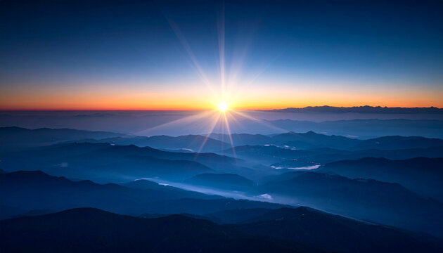 Dramatic sunrise over mountain range with radiant sunlight and atmospheric haze