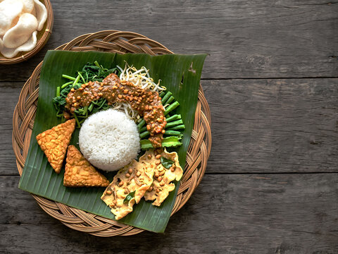 Authentic indonesian Nasi pecel with vegetables , peanut sauce, fried tempeh, peanut crackers, flat lay and copy space