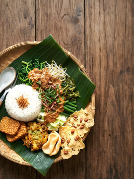 Indonesian local cuisine Nasi pecel with steam vegetables, fried tempeh, peanut crackers, bakwan  and peanut sauce , flat lay with copy space