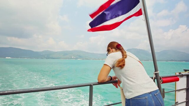 Woman Standing On Ferry Deck Looking At Turquoise Sea With Thai National Flag Symbolizing Island Travel And Sea Journey