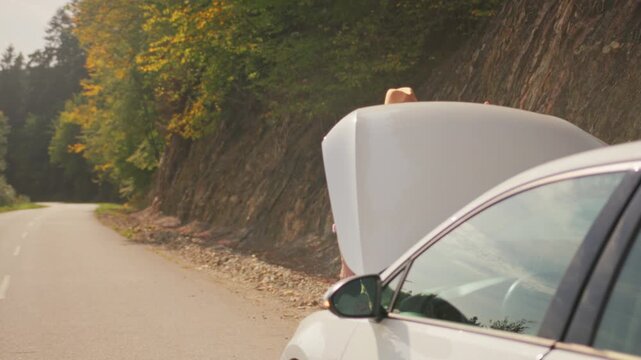 Man waiting worried, Distressed man standing near rural road showing worry with open car hood amid fall foliage