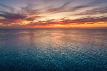 Fototapeta premium Vibrant and colorful sunset over calm ocean horizon