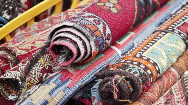 Close up of rolled up oriental rugs with detailed patterns and textures, displaying vibrant colors