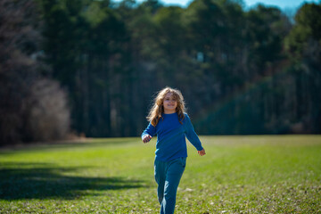 Fototapeta premium Child running on field. Happy kid running outdoors. Child jumping and running in nature. Child running in a meadow. Summer fun for active child. Playful kid freedom. Free childhood in nature.