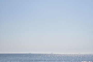 Obraz premium Calm Ocean Horizon with Distant Cargo Ships.