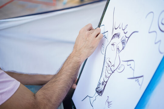 Artist drawing a humorous caricature portrait on a white canvas with black ink