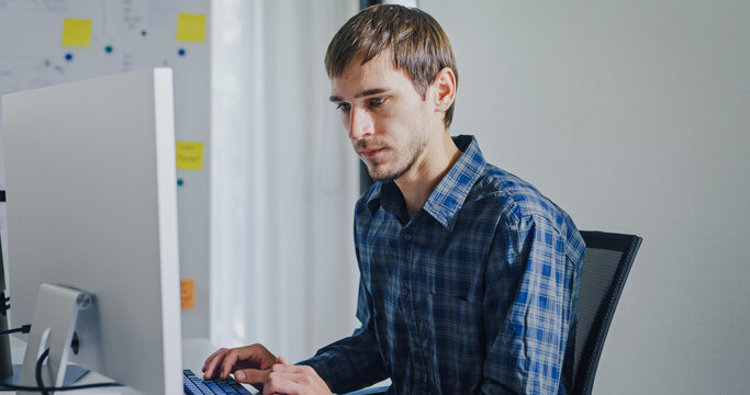 Young adult male freelance developer typing write prompt AI bot app program nomad terminal with coding at office. Artificial intelligence dashboard, robotics, user interface, machine learning concept.
