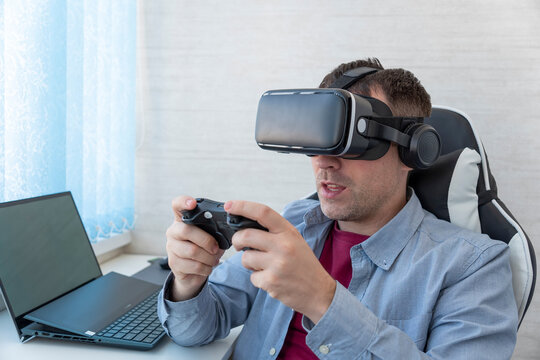 Young man wearing VR goggles while playing video games in virtual world. Feeling excited and amazed.
