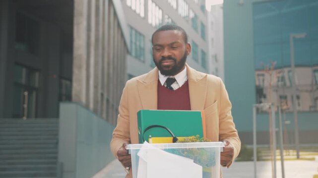 Employee leaving with belongings in hand, Individual exiting workplace carrying personal items and folders