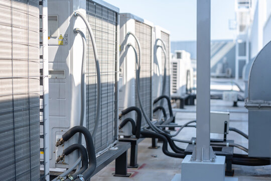 Row of industrial air conditioning units on a building rooftop, External hvac system installed on the roof of a modern commercial office, Modern outdoor air conditioner compressor units