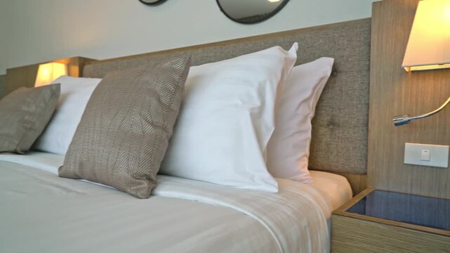 Comfortable bed with pillows and a wall lamp above a nightstand with outlets and switches