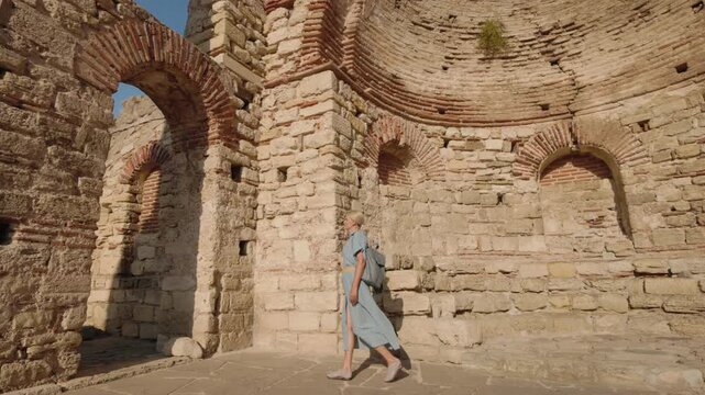 Woman exploring ancient ruined church interior with brick arches in Nessebar Bulgaria