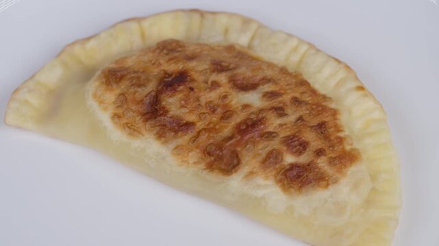 Crispy meat pastry. Fried cheburek with crispy crust. Delicious streetstyle cheburek with crunchy crust and flavorful meat filling presented on plain white background