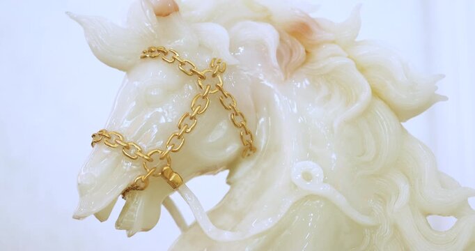 White jade horse sculpture with gold chain on clean background. Luxury and auspicious symbol representing wealth, prosperity and premium lifestyle concept