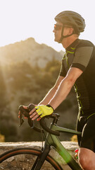 Fototapeta premium Cyclist resting with bike at sunset in a mountainous area