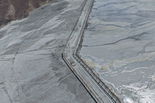 Aerial view of a huge mining tailings dam next to a reservoir and storage tank