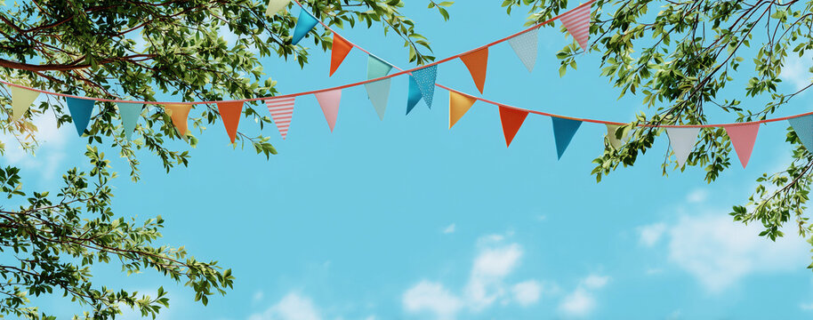 colorful bunting and flags hanging from tree branches against a blue sky background.