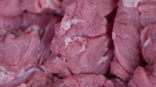 Uncooked meat closeup. Fresh meat pieces with pink and white stripes. Highdetail macro shot of uncooked beef chunks highlighting marbling and chill effects from market lighting