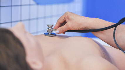 Fototapeta premium Medical professional using stethoscope on training mannequin during clinical simulation course