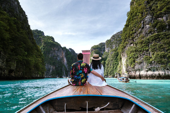 A romantic moment unfolds as a couple enjoys a scenic boat ride in Koh Phi Phi, Thailand. Vibrant cliffs and turquoise waters create a breathtaking backdrop for this travel adventure.
