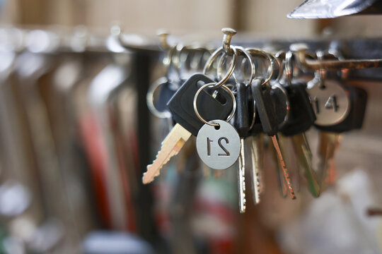 Close up metal keys hanging on rack ring hook tag organization security safety concept background blurred depth of field vintage style lock safe open close home room hotel service door entrance