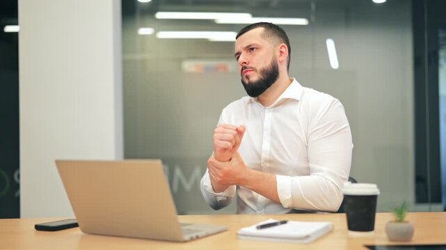 Office worker experiences noticeable wrist pain working at laptop. Discomfort creates emotional struggle and hints at potential overexertion or ergonomic issues. Common work-related health problem.