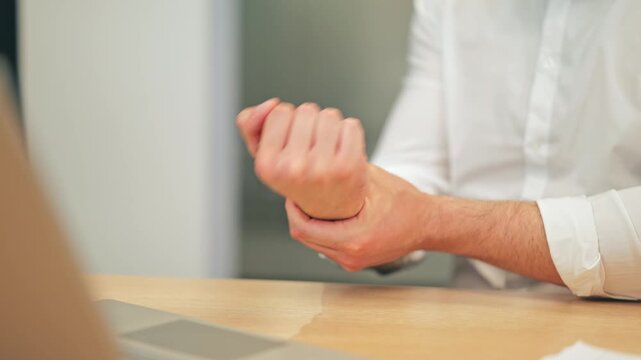 Experiencing significant wrist pain and discomfort while working at a desk. Manifestation of strain or repetitive stress injury from prolonged computer use, requiring attention and relief.