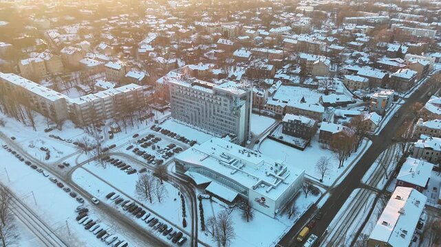 Aerial view of Riga city covered in snow with urban buildings and winter atmosphere at sunset.
