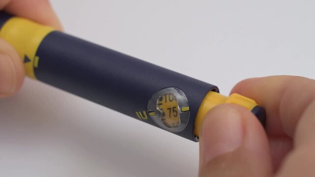 Patient dialing the dosage on an injector pen for hormone therapy, isolated on a white background