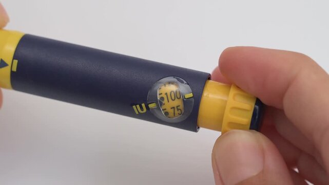 Person is adjusting the dosage dial on a follicle stimulating hormone injection pen