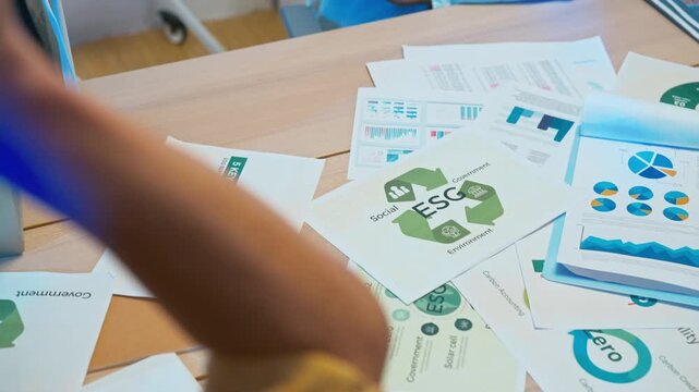 Close up of diverse team stacking hands together and raising them up to celebrate commitment to ESG, social responsibility, and environmental projects.