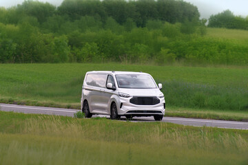 Fototapeta premium Small business delivery van driving in scenic landscape