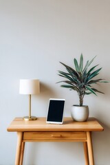 Fototapeta premium Simple wooden table holds lamp, tablet, and potted plant