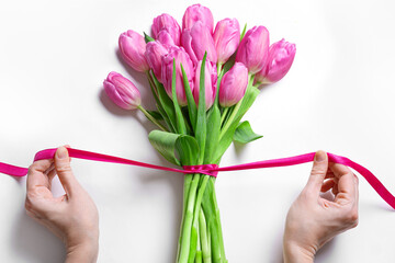 Woman hands tying pink ribbon on tulips, Mother's Day