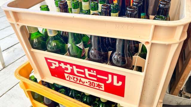 Asahi Beer crate full of empty glass bottles from Kirin Heartland and Wilkinson Ginger Ale ready for recycling collection - Tokyo, Japan, September 23, 2024