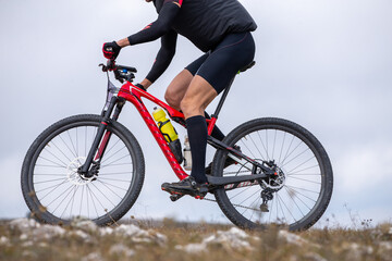 Fototapeta premium Close-up cyclist riding red mountain bike on rocky trail