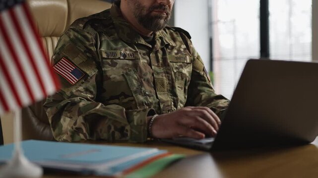 American army intelligence officer analyzing data and typing reports on laptop