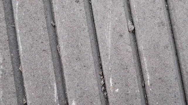 Close-up of grooved concrete texture with parallel lines. Professional cinematic pan of grey industrial cement surface. High-quality architectural material.