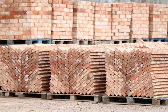 Large outdoor storage of ceramic bricks on pallets. Wholesale building materials supply at a brickyard factory