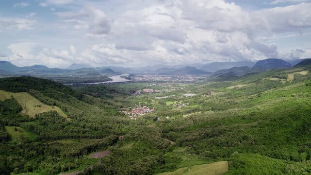 Slow hovering forward motion flying view of mountainous tropical landscape, with sunny cloudy hazy environment in the background.
