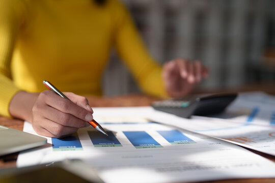 Business person's hands analyzing financial budget reports and data on paper documents, using a calculator to manage finance, accounting, and economic planning